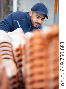 construction worker checking roof tiles for installation. Стоковое фото, агентство Ingram Publishing / Фотобанк Лори