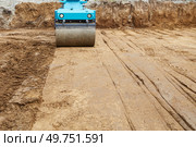 Construction site features a blue roller compacting earth on a freshly excavated ground during daylight hours. Стоковое фото, фотограф Виктория Тельминова / Фотобанк Лори
