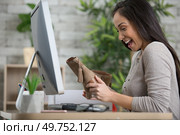 smiling woman unboxing a postal parcel with her new purchases. Стоковое фото, агентство Ingram Publishing / Фотобанк Лори