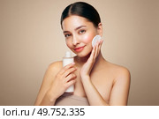 Young girl holds cotton pad while cleansing face with cosmetic milk. Skin care removal of makeup cleansing. Basic facial skin care. Стоковое фото, агентство Ingram Publishing / Фотобанк Лори