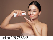 Beautiful woman with bottle of moisturizer cream. Video of woman with perfect skin on beige background. Beauty and Skin care concept. Стоковое фото, агентство Ingram Publishing / Фотобанк Лори
