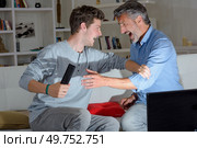 Father and son play fighting over remote control. Стоковое фото, агентство Ingram Publishing / Фотобанк Лори