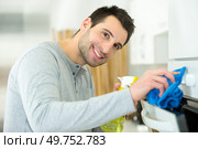 man wiping the oven. Стоковое фото, агентство Ingram Publishing / Фотобанк Лори