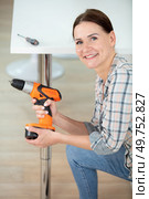happy woman using hand drill to assemble a table. Стоковое фото, агентство Ingram Publishing / Фотобанк Лори