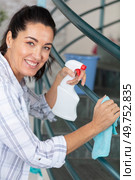 long-haired housewife cleaning stair railings with rag at home. Стоковое фото, агентство Ingram Publishing / Фотобанк Лори