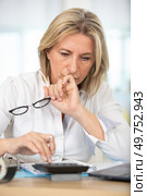 mature woman with calculator makes up her personal budget. Стоковое фото, агентство Ingram Publishing / Фотобанк Лори