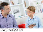 Father scolding young boy holding electronic device. Стоковое фото, агентство Ingram Publishing / Фотобанк Лори