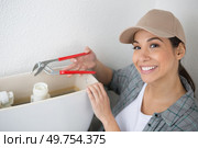 happy woman plumber is fixing the toilet flush. Стоковое фото, агентство Ingram Publishing / Фотобанк Лори