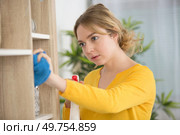 a young lady dusting bookshelves. Стоковое фото, агентство Ingram Publishing / Фотобанк Лори