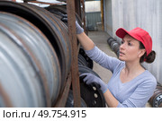 Woman looking at wheel rims in racking. Стоковое фото, агентство Ingram Publishing / Фотобанк Лори