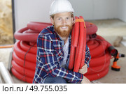 workman crouching down holding red pipe. Стоковое фото, агентство Ingram Publishing / Фотобанк Лори