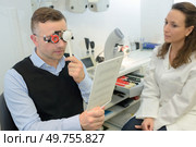 doctor showing special lenses to male customer. Стоковое фото, агентство Ingram Publishing / Фотобанк Лори