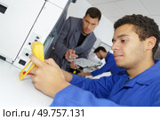 young technician using mutimeter under teachers supervision. Стоковое фото, агентство Ingram Publishing / Фотобанк Лори