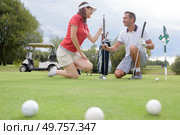 Couple crouching on golf course. Стоковое фото, агентство Ingram Publishing / Фотобанк Лори