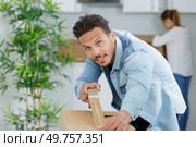 man taping boxes for moving in new apartment. Стоковое фото, агентство Ingram Publishing / Фотобанк Лори