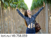 A joyful young woman stands among vibrant trees, arms wide open, celebrating natures beauty and her newfound freedom, feeling grateful for her surrounds and the happiness they bring daily. Joyful Woman Embracing and Connecting with Nature in a Beautiful Lush Green Environment. Стоковое фото, агентство Ingram Publishing / Фотобанк Лори