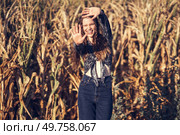 In a sunny, vibrant cornfield on a beautiful day, a joyful young woman with curly hair radiates pure happiness as she cherishes her deep connection with the stunning natural beauty surrounding her. A carefree woman joyfully plays in a sunny cornfield, embracing lifes beauty around her. Стоковое фото, агентство Ingram Publishing / Фотобанк Лори