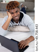 casual young man laying on floor at home with laptop. Стоковое фото, агентство Ingram Publishing / Фотобанк Лори