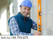 happy worker checks erected brick wall with level. Стоковое фото, агентство Ingram Publishing / Фотобанк Лори