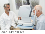 Senior man looking into eye testing machine. Стоковое фото, агентство Ingram Publishing / Фотобанк Лори