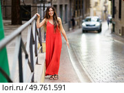A joyful woman in a stylish red dress walks confidently down a charming street, radiating elegance against a captivating urban backdrop, enchanting and bringing smiles to those around her. A charming woman in a vibrant red dress strolls gracefully through a scenic European street. Стоковое фото, агентство Ingram Publishing / Фотобанк Лори
