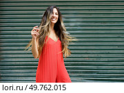 A cheerful woman joyfully beams in a stylish red dress, beautifully captured against a striking textured green background, making this image ideal for various fashion and lifestyle themes. A Joyful Woman Dressed in a Vibrant Red Dress Posing Gracefully Against a Lively Green Backdrop. Стоковое фото, агентство Ingram Publishing / Фотобанк Лори