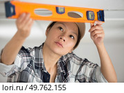 woman measuring the ceiling with sprit level. Стоковое фото, агентство Ingram Publishing / Фотобанк Лори