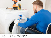 man in wheelchair repairs a tumble dryer. Стоковое фото, агентство Ingram Publishing / Фотобанк Лори