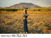 A carefree woman stands joyfully in a vast golden field, her arms wide open as she embraces the stunning beauty of the majestic mountains, which are illuminated by the warm, golden rays of the sunset. Joyful Woman in Nature Embracing the Essence of Freedom in a Beautiful Scenic Landscape. Стоковое фото, агентство Ingram Publishing / Фотобанк Лори