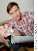 Man putting plastic glue on end of pvc pipe. Стоковое фото, агентство Ingram Publishing / Фотобанк Лори