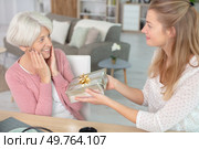 young lady offering a gift to her thrilled grandmother. Стоковое фото, агентство Ingram Publishing / Фотобанк Лори