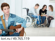 young man playing a guitar in a school. Стоковое фото, агентство Ingram Publishing / Фотобанк Лори