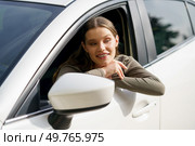 A cheerful woman leans out of her car window during a scenic drive, savoring her beautiful surroundings. Her bright smile reflects positivity, joy, and a sense of freedom on this wonderful day. A Cheerful Young Woman Feeling Joy and Happiness While Enjoying a Scenic Drive in Her Car. Стоковое фото, агентство Ingram Publishing / Фотобанк Лори