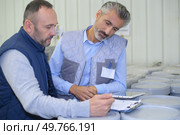 manager noting on clipboard and worker taping box in warehouse. Стоковое фото, агентство Ingram Publishing / Фотобанк Лори