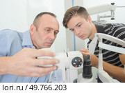 Optician and trainee seting up machinery. Стоковое фото, агентство Ingram Publishing / Фотобанк Лори