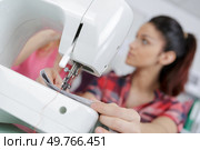 young woman sewing on sewing-machine focus on sewing-machine. Стоковое фото, агентство Ingram Publishing / Фотобанк Лори