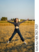 In a beautiful sunlit field, a happy young woman leaps joyfully, her carefree spirit capturing the essence of freedom and pure spontaneity, surrounded by vibrant golden grass swaying in the breeze. A Joyful Young Woman Jumping Happily in a Golden Field Under the Beautiful Sunset. Стоковое фото, агентство Ingram Publishing / Фотобанк Лори