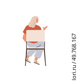 A woman with blonde hair sits on a chair, facing away, wearing a red top, light blue pants, and sandals, gesturing with one hand. Ideal for counseling, communication, talking, meeting, listening. Woman Sitting and Gesturing While Seated on a Chair in Casual Attire. Стоковая иллюстрация, агентство Ingram Publishing / Фотобанк Лори