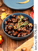 Cracked roasted chestnuts, roasted chestnuts some chestnuts split open , garnished with fresh rosemary, styled with autumn leaves.. Charred roasted Chestnuts. Стоковое фото, агентство Ingram Publishing / Фотобанк Лори