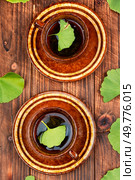 A cup of herbal tea, green Ginkgo biloba leaves on a rustic wooden background.. Ginkgo tee with freshen leaf. Стоковое фото, агентство Ingram Publishing / Фотобанк Лори
