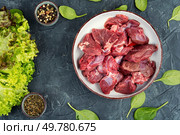 Raw venison slices arranged with fresh fragrant herbs on a concrete kitchen table.. Sliced raw venison deer meat for a stew. Стоковое фото, агентство Ingram Publishing / Фотобанк Лори