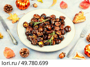 Cracked roasted chestnuts, roasted chestnuts some chestnuts split open , garnished with fresh rosemary, styled with autumn leaves.. Warm roasted chestnuts served on a plate. Стоковое фото, агентство Ingram Publishing / Фотобанк Лори