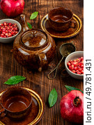 Delicious red tea and pomegranate on table in the teakettle.. Tea With Pomegranate Seeds. Стоковое фото, агентство Ingram Publishing / Фотобанк Лори