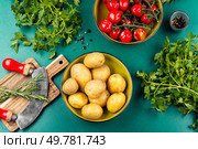 Kitchen table with fresh vegetables, raw potatoes, fresh beautiful tomatoes and bunches of greens. Top view.. Fresh raw potatoes and bunch of wet ripe tomatoes. Стоковое фото, агентство Ingram Publishing / Фотобанк Лори