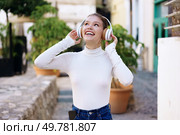 In an urban setting, a cheerful young woman with stylish headphones joyfully listens to music outdoors, embodying happiness, relaxation, and the exhilarating freedom that music brings. Joyful young woman enjoying the bliss of outdoor music while wearing her headphones. Стоковое фото, агентство Ingram Publishing / Фотобанк Лори