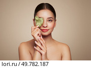 Beauty young woman doing skin care routine, scrapping, massage facial skin with jade gua sha scrapper, Facial treatment for anti aging and cosmetic cleaning. Стоковое фото, агентство Ingram Publishing / Фотобанк Лори