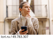 In a bustling urban environment, a young professional confidently and thoughtfully uses her smartphone, embodying a perfect blend of style and assurance amid the citys dynamic atmosphere. A young professional focuses on their smartphone amid a lively, energetic urban setting. Стоковое фото, агентство Ingram Publishing / Фотобанк Лори