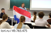 Adult female teacher showing the flag of the Netherlands to students. Стоковое видео, видеограф Яков Филимонов / Фотобанк Лори