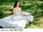 Young woman is resting on a mattress in the lotus position, in summer forest. Girl is sleeping in the woods. Стоковое фото, агентство Ingram Publishing / Фотобанк Лори