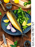 Whole smoked headless mackerel, scomber on a plate with greens, lime and spices.. Smoked headless fragrant fish mackerel. Стоковое фото, агентство Ingram Publishing / Фотобанк Лори